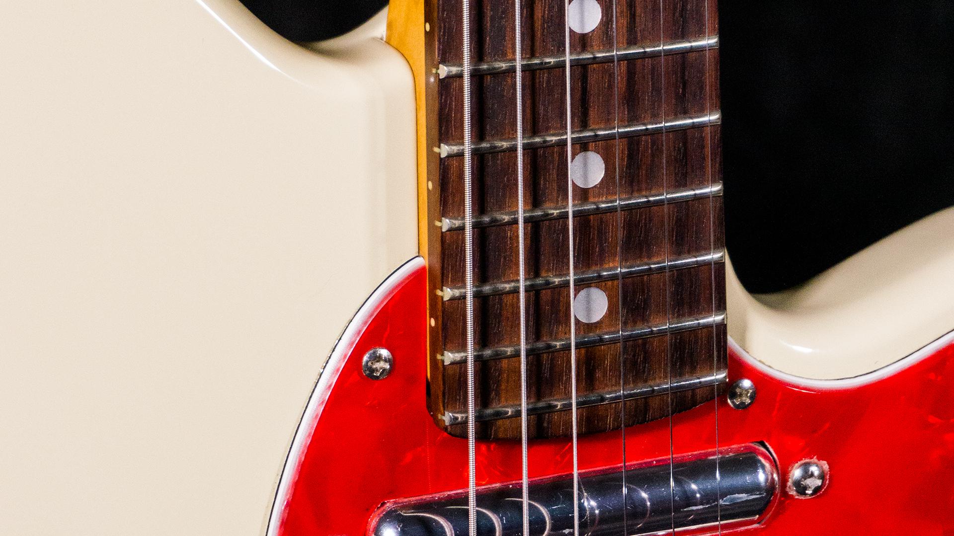 Closeup view of an Ivory (IV) TC530 fretboard and red pearloid pickguard